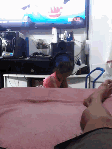 a person laying on a bed in front of a tv that says netflix on it