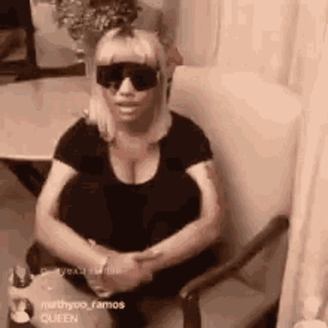 a woman is sitting in a chair with her legs crossed and wearing sunglasses .