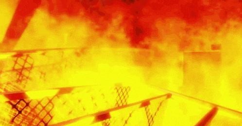 a building is on fire with a lot of flames coming out of it and a fence in the foreground .