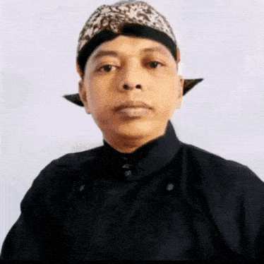 a man wearing a leopard print hat and a black shirt is looking at the camera .