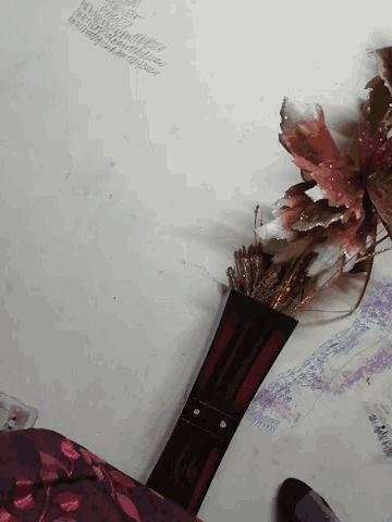 a vase with flowers in it is sitting on a white wall