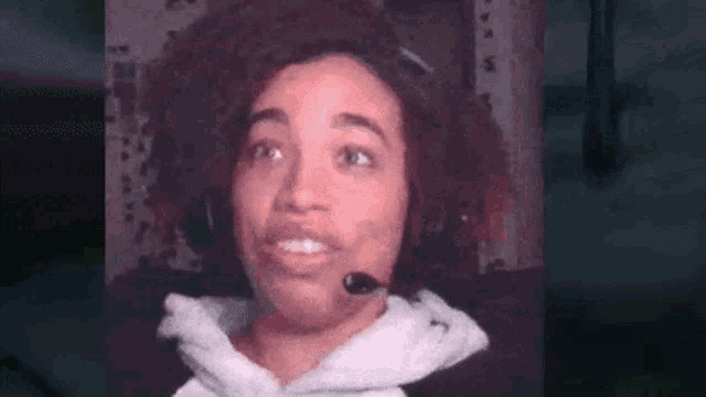 a woman wearing headphones and a microphone is making a face .