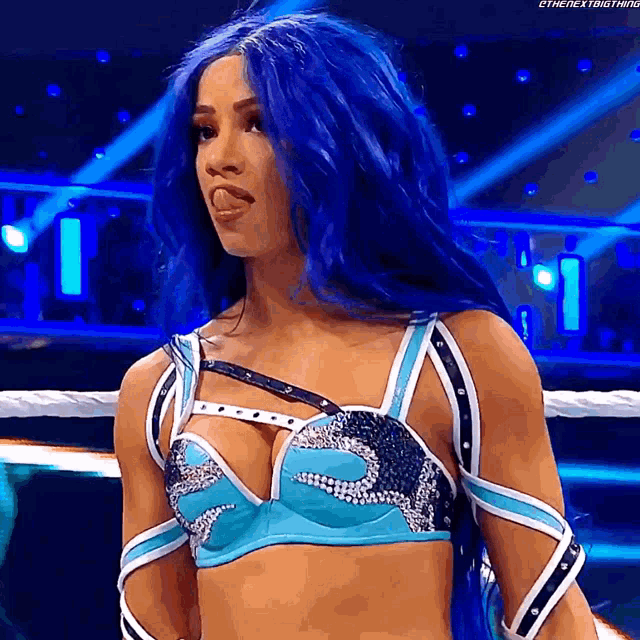 a woman with blue hair is standing in a wrestling ring