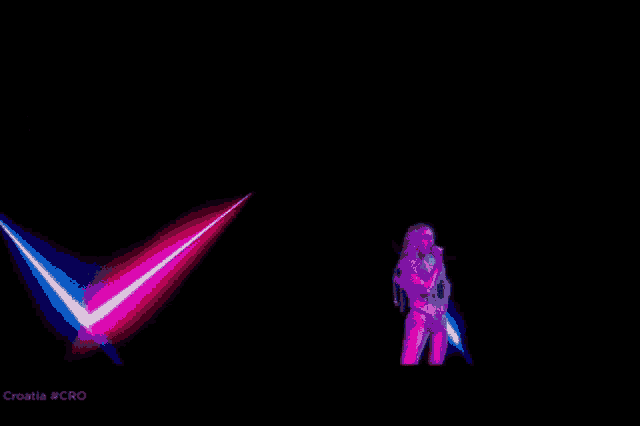 a woman is singing into a microphone on a stage in front of a pink light
