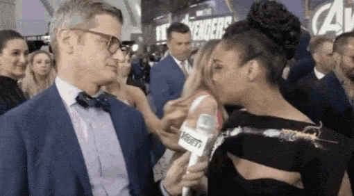 a woman is kissing a man while holding a variety microphone ..