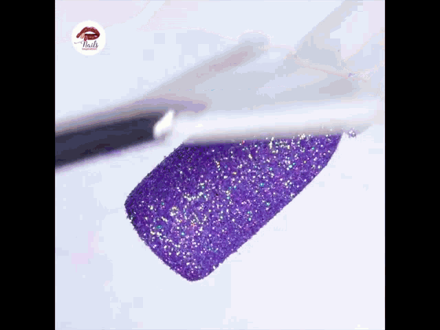 a brush is being used to apply purple glitter to a nail .