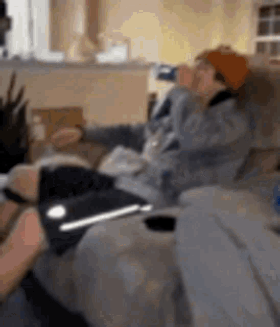 a man is sitting on a couch drinking a bottle of beer .