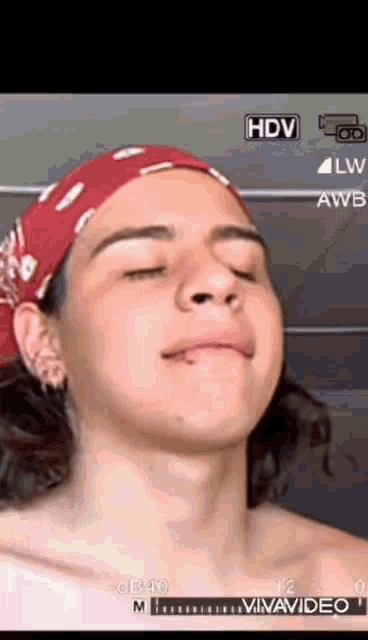 a young man wearing a red bandana is being filmed by a camera with hdv written on it