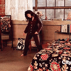 a woman is dancing in a bedroom with a bed that says city on the bottom