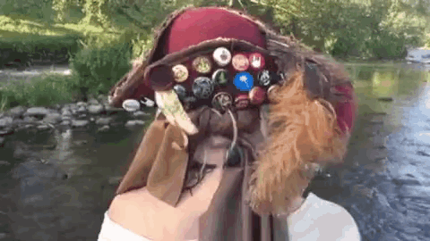 a person wearing a hat with buttons and feathers on it
