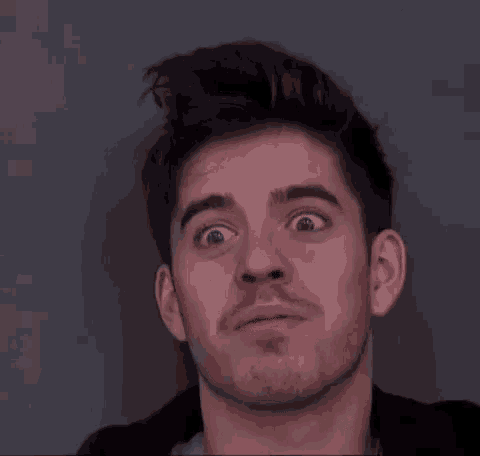 a young man with a beard is making a funny face with his eyes wide open .