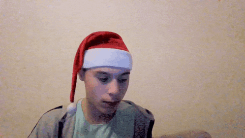 a man wearing a santa hat is making a hand gesture