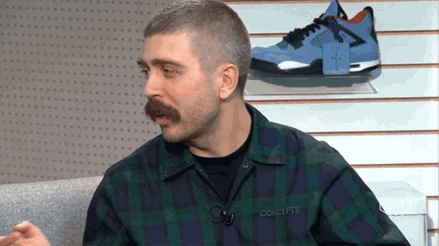 a man wearing a plaid shirt with the word concepts on the front