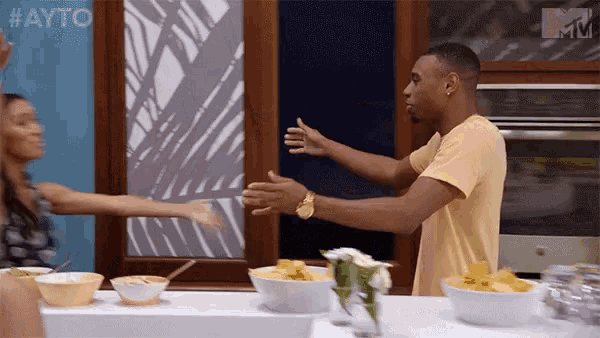 a man and a woman are hugging in a kitchen with a sign that says #ayo