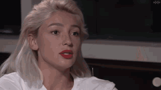 a woman with blonde hair and red lips is wearing a white shirt .