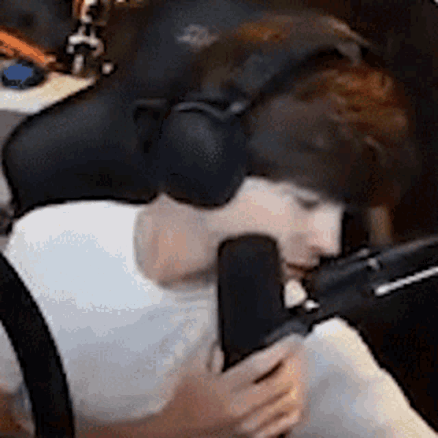 a man wearing headphones is sitting in front of a microphone and talking into it .