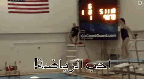 a woman is jumping into a swimming pool in front of a scoreboard that says 5