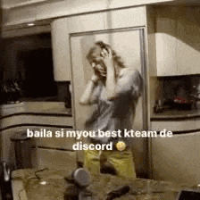 a woman is standing in front of a mirror in a kitchen talking on a phone .