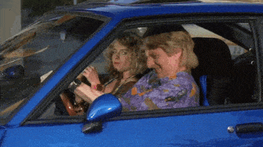 a man and a woman sit in a blue car