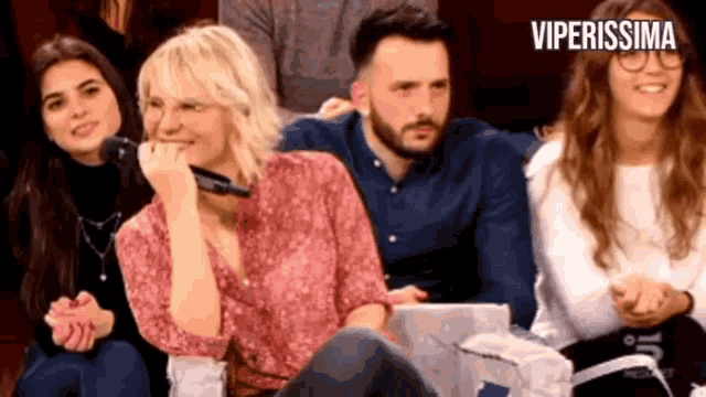 a group of people are sitting in front of a sign that says viperissima on it
