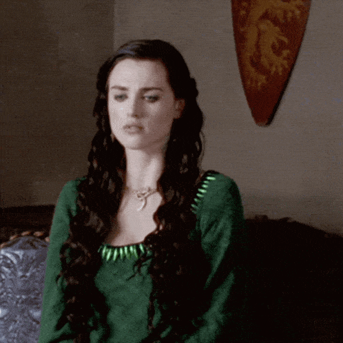 a woman in a green dress stands in front of a shield