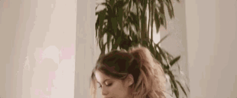 a woman with long hair is standing in front of a plant .