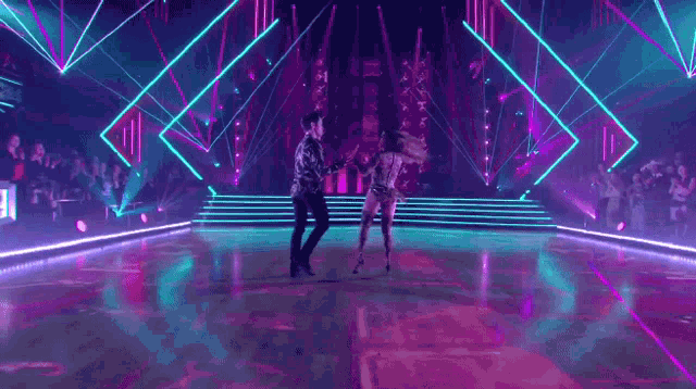 a man and a woman are dancing on a dance floor in a dark room .