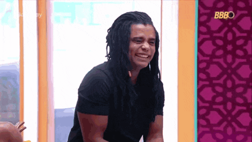 a man with dreadlocks is laughing in front of a wall that says bb80
