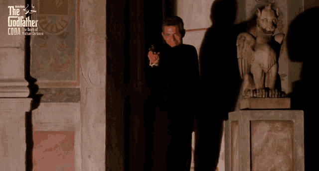 a poster for the godfather shows a man pointing a gun at a gargoyle statue
