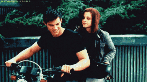 a man is riding a motorcycle next to a woman who is standing behind him and the words skyfallmodellife tumblr are visible