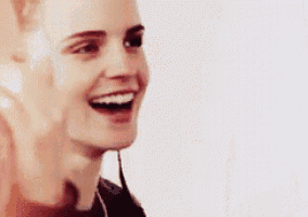 a close up of a woman laughing with her mouth open and her hands on her face .