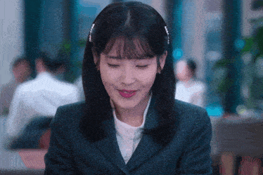 a woman in a suit is smiling and looking down