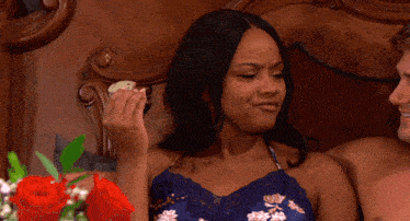 a man and a woman are laying on a bed and the woman is holding a piece of food in her hand