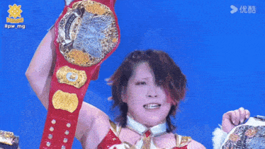 a woman in a red and gold outfit is holding up a wrestling belt