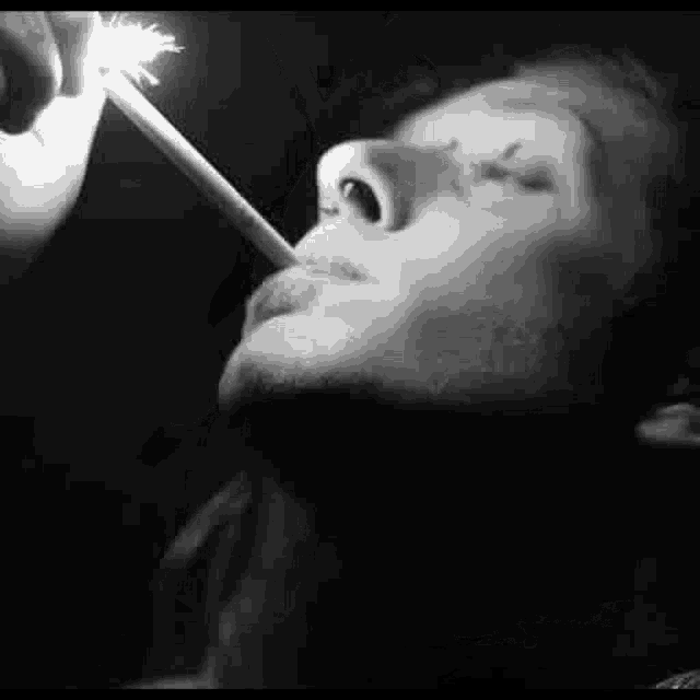 a man is smoking a cigarette with a lighter in his mouth .