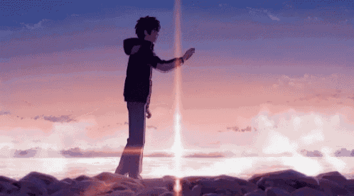 a man is standing on top of a rocky cliff overlooking the ocean at sunset .