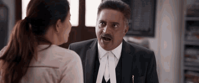 a man in a suit is talking to a woman in a ponytail