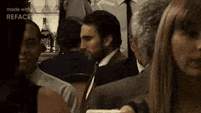 a man in a suit and tie is standing in a crowd of people in a bar .