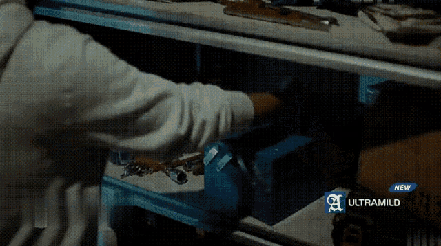 a person is reaching into a drawer with a new ultramild advertisement in the background