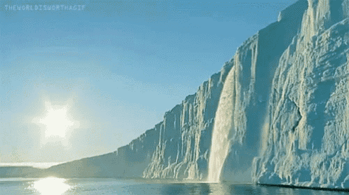 a waterfall is coming down a snowy cliff into the ocean