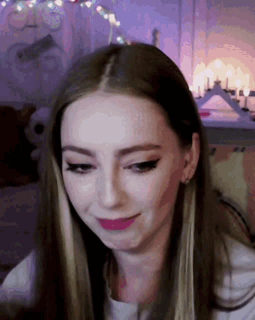 a close up of a woman 's face with a candle in the background