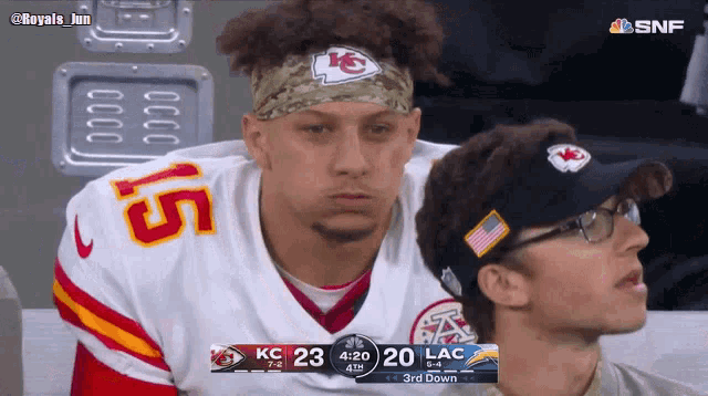 a man wearing a kc jersey sits next to another man