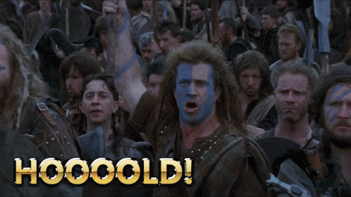 a man with blue and white paint on his face shouts hooooold in front of a crowd of men
