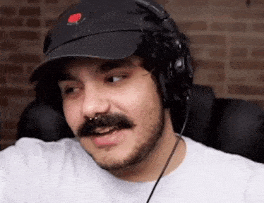 a man with a beard is wearing a hat and headphones .