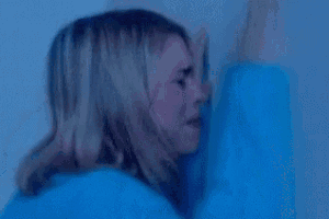 a woman in a blue shirt is covering her face with a blue blanket .