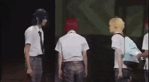 a group of young men are standing on a stage in a dark room .