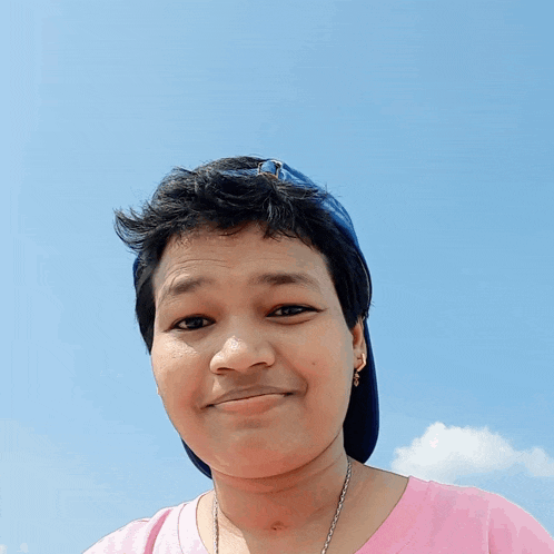a young woman wearing a pink shirt and a blue hat makes a funny face