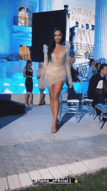 a woman in a short dress is walking down a runway in front of a sign that says lorjo palace