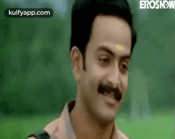 a man with a mustache is making a funny face and smiling .