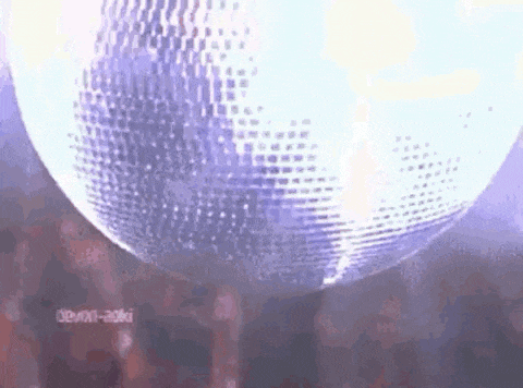 a disco ball is spinning in front of a crowd of people .
